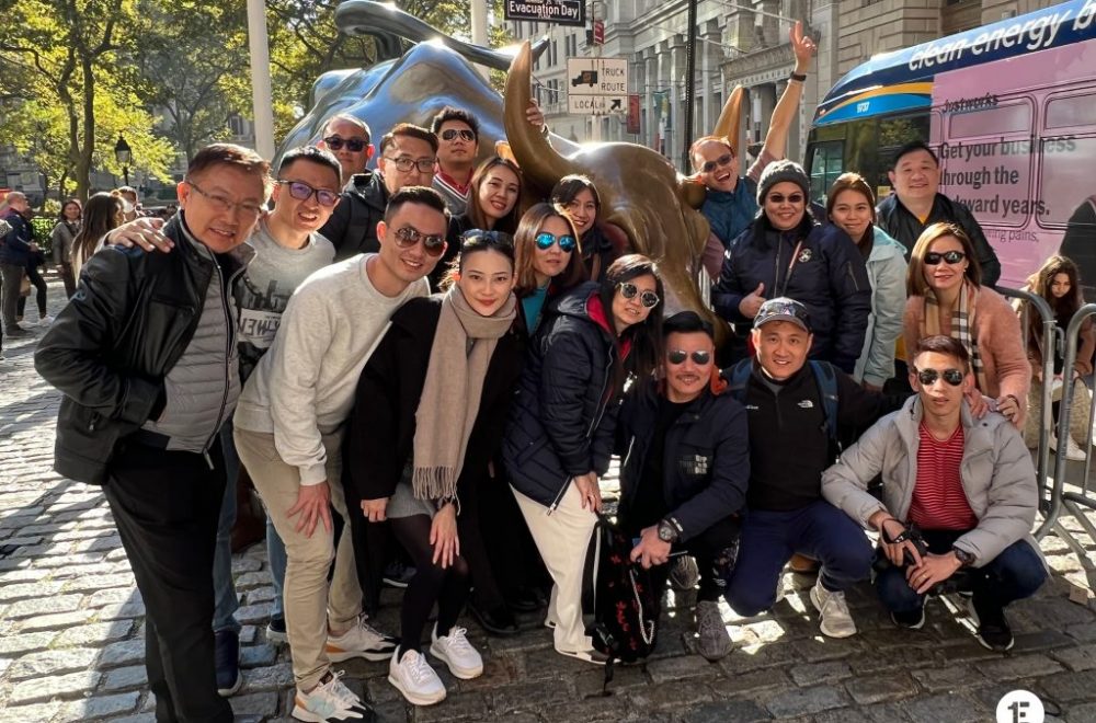 Group posing with bull statue on Wall Street tour