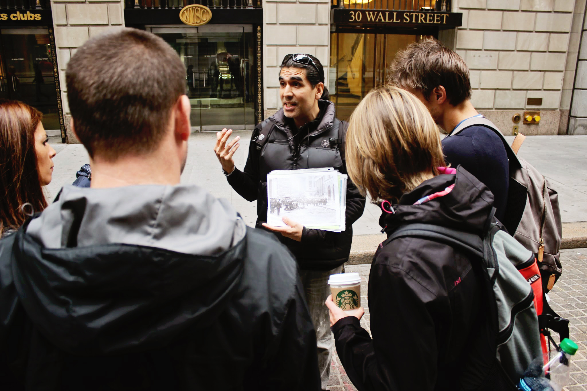 Wall Street Insider Tour guide showing historical photos near 30 Wall Street